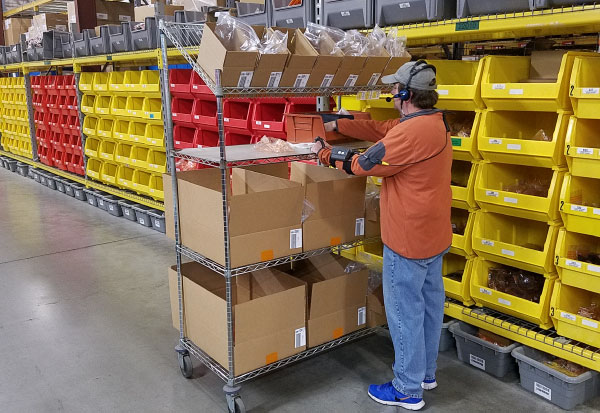 Warehouse worker with mobile scanner at shelving bay